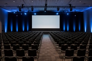 A big corporare event with a stage and a lot of chairs for an empty audience.