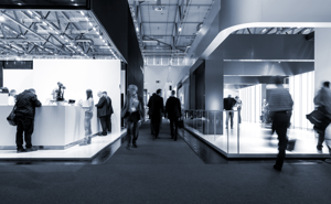 Black and white photography of two busy exhibition booths, representing EXCITE's and ET GLOBAL's common interest: exhibitions stands.