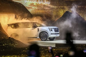 Ein weißer SUV steht auf einer vernebelten Plattform mit künstlichen Bergen und Hügeln im Vor- und Hintergrund.