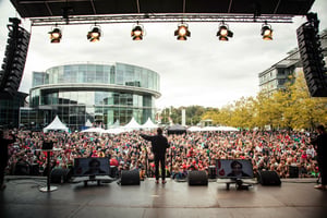 A large-scale event as seen from the perspective of a presenter on stage, looking out at the large audience.