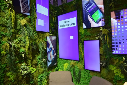 LED displays mounted vertically and set into walls covered in greenery and moss.