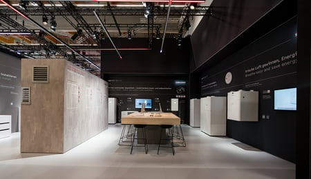 A view of part of the STIEBEL ELTRON stand at the ISH HVAC trade fair, featuring a spacious seating area and an unobtrusive air-conditioning unit.