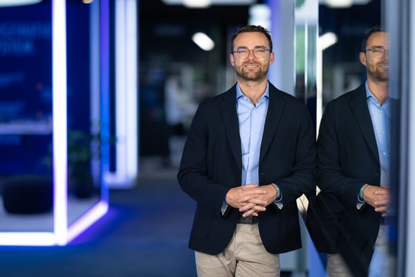 Geschäftsführer von octanorm steht in einem modernen, modular aufgebauten Messeumfeld mit LED‑Lichtelementen und reflektierenden Flächen, exemplarisch für modulare Markenräume im Messebau.