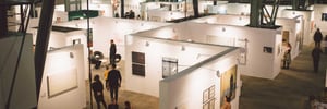 Modular exhibition stands, viewed from above, with white walls and visitors looking at the exhibits.