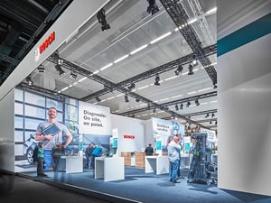 Weitere Ansicht des BOSCH-Messestandes auf der Automechanika-Messe mit Besuchern und Schriften auf der Wand.